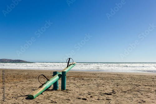 Empty wooden teeter totter on sunny day in La Serena beach, Chile. Kids fun zone, playground concept