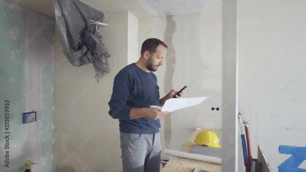 Man looks absorbed while checking project and using smartphone, steadycam shot
