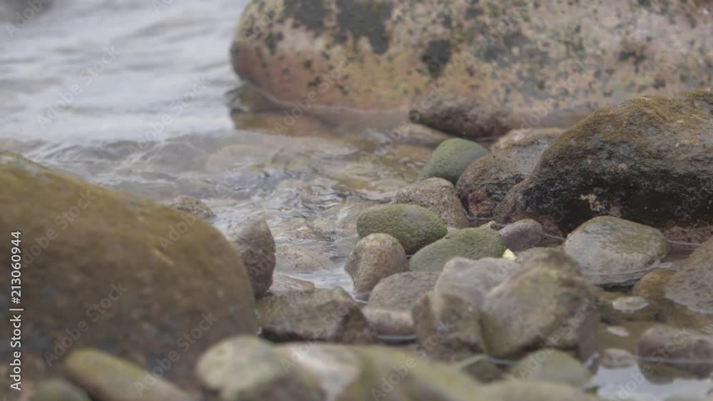 Slowmotion shot of water covering rocks at the shore