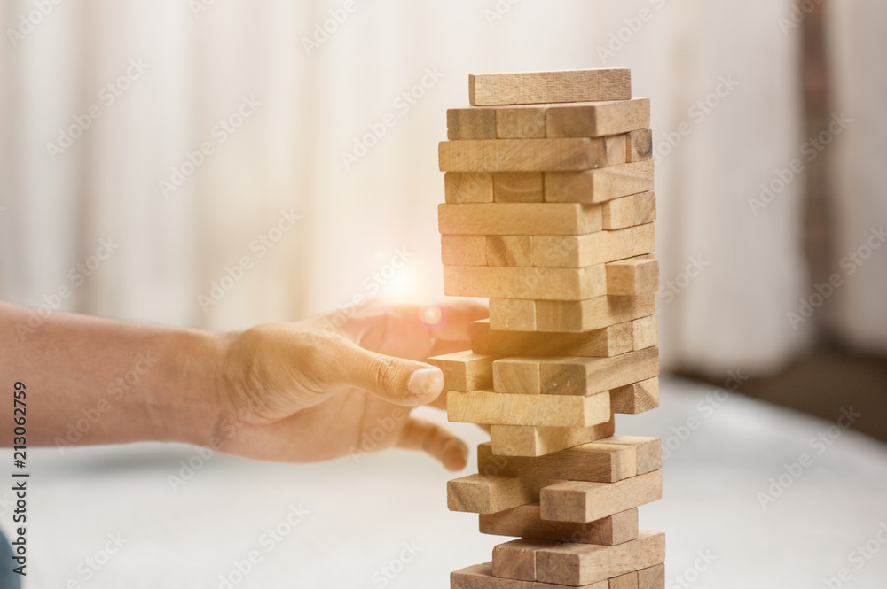 hand pulling out or placing wood block on the tower.plan and strategy in business. blur for background. hand pulling out or placing wood block on the tower.plan and strategy in business. blur for background.