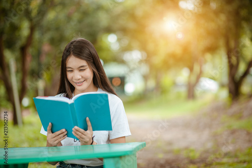 Asian girl reading book at park in summer sunset light. asian woman reading book in Thailand. asian Beautiful woman reading a book at table.