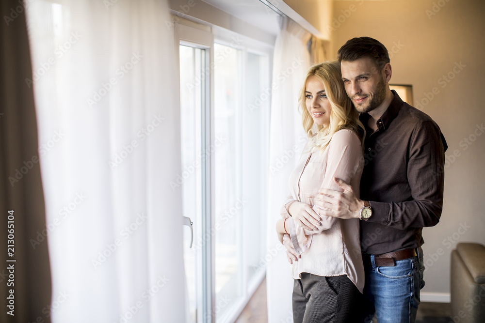 Young couple standing by the window in the room Young couple standing by the window in the room