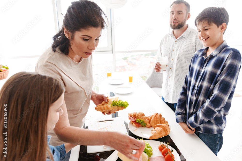 Portrait of european family woman and man with children having breakfast together, in bright kitchen in apartment