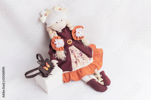 Doll for the interior of hand made of fabric and thread.The doll is dressed in a dress and a coat. Two of her braids are decorated with flowers. Doll schoolgirl.