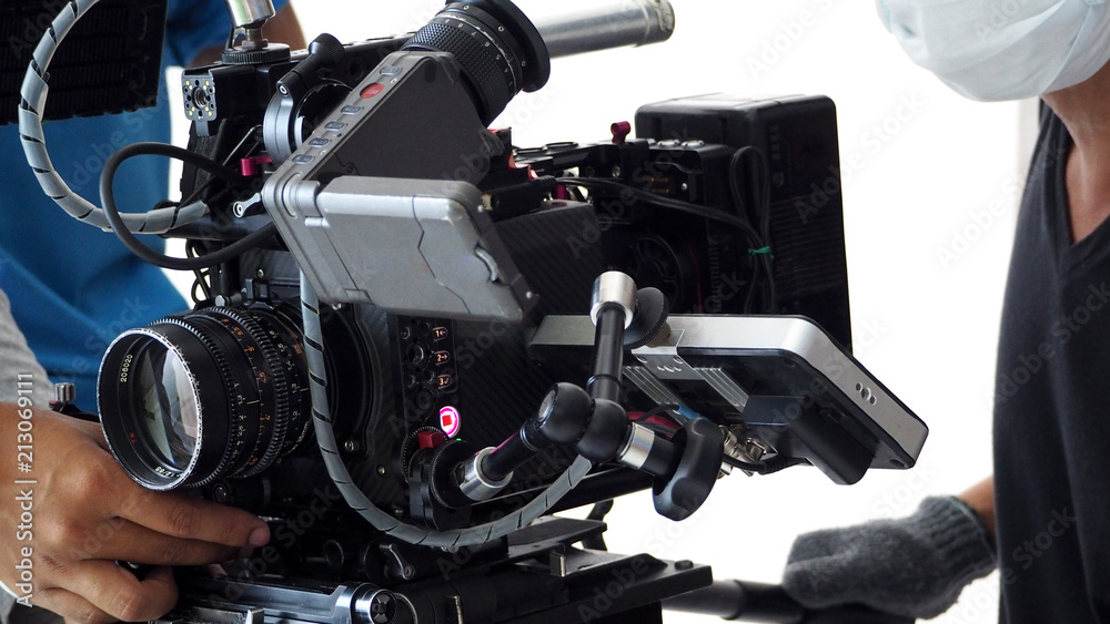Video camera ultra high definition on pan and tilt head professional tripod with rig and gimbal operated by film crew team that recording or shooting tvc movie at location with monitor. Video camera ultra high definition on pan and tilt head professional tripod with rig and gimbal operated by film crew team that recording or shooting tvc movie at location with monitor.