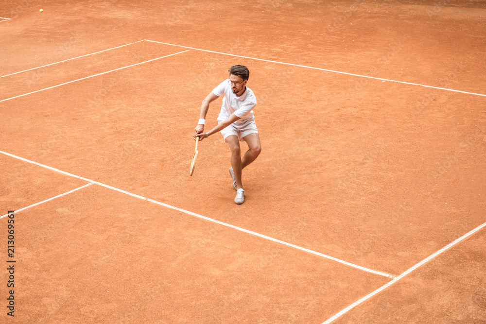 retro styled male tennis player with racket playing game on tennis court