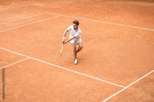 retro styled male tennis player with racket playing game on tennis court © LIGHTFIELD STUDIOS