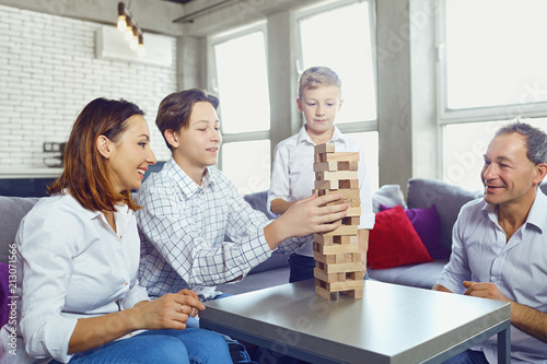 The family plays board games gaily while sitting at the table inside the room.