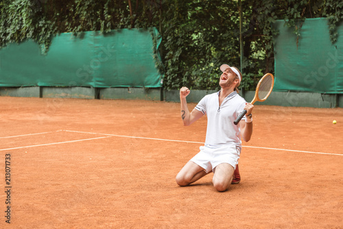blond winner with racket celebrating and kneeling on tennis court © LIGHTFIELD STUDIOS