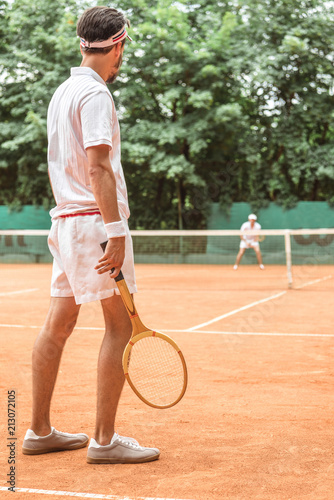 back view of man playing tennis with wooden racket on tennis court © LIGHTFIELD STUDIOS