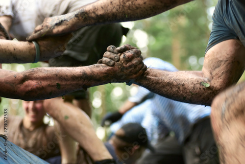  Folks help each over in a mud race with obstacle course. In a motion.
