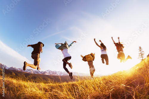Group happy friends runs and jumps mountains sunset photo