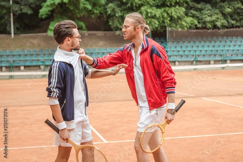 angry sportsmen with wooden rackets conflicting on tennis court © LIGHTFIELD STUDIOS