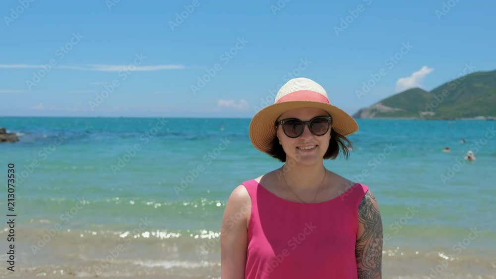 Beautiful young brunette woman wearing a bathing suit and sun hat, sunglasses, standing on a ferry deck, enjoying rest, beauty of the sea, happy, smiling Beautiful young brunette woman wearing a bathing suit and sun hat, sunglasses, standing on a ferry deck, enjoying rest, beauty of the sea, happy, smiling
