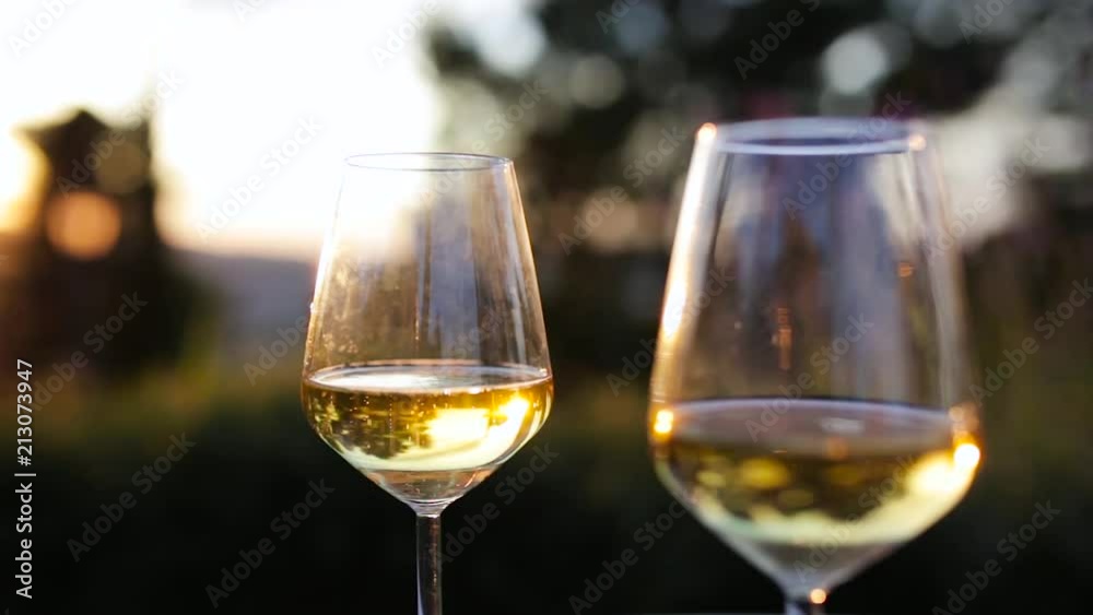 Couple of glasses of white wine sparkling backlit at sunset Couple of glasses of white wine sparkling backlit at sunset