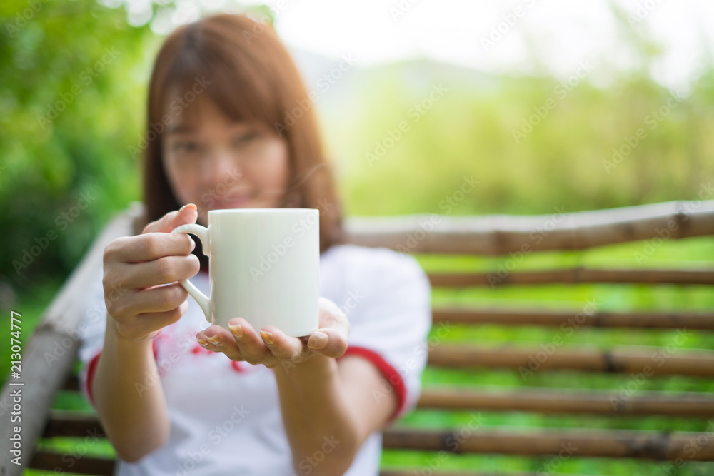 Hot coffee cup in hand of asian woman blur background.Concept ralaxing image.