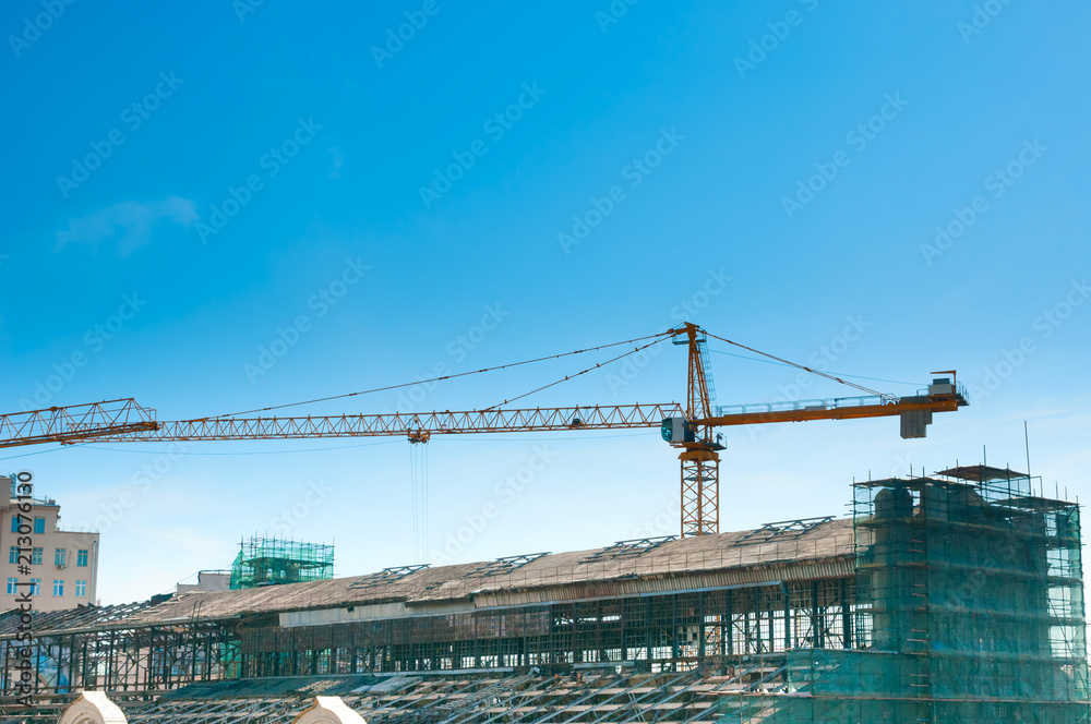 Crane and building under construction on blue sky background Crane and building under construction on blue sky background