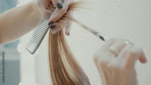 Female hairdresser cutting hair tips with hairdressing scissors in beauty salon. photo