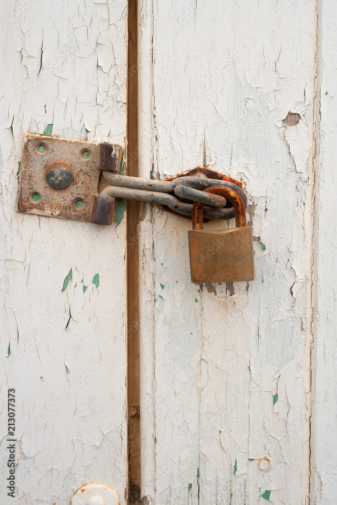 A padlock on a wooden door with peeling paint A padlock on a wooden door with peeling paint