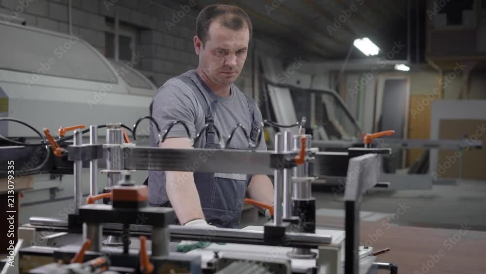 Factory worker man in overall standing near machine in plant room Factory worker man in overall standing near machine in plant room