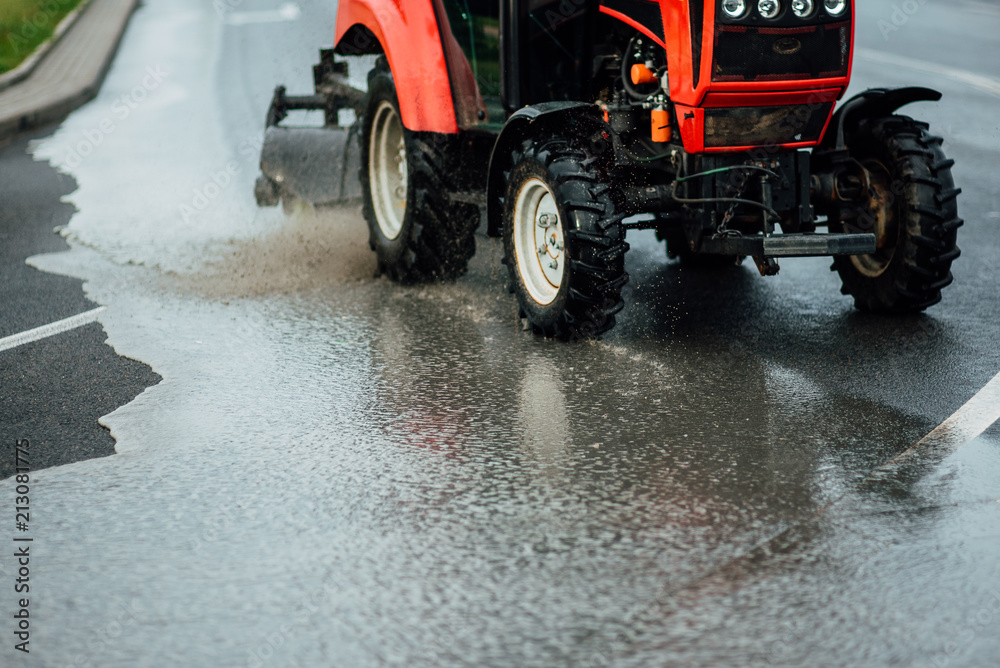 Cleaning sweeper machines washes the city asphalt road with water spray.