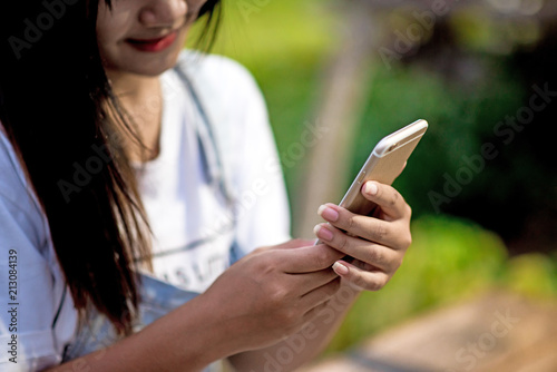 Mockup image of a woman holding and displaying a white mobile phone with a black screen with a blank screen on a table in a modern cafe. Ideas for working with communication tools.