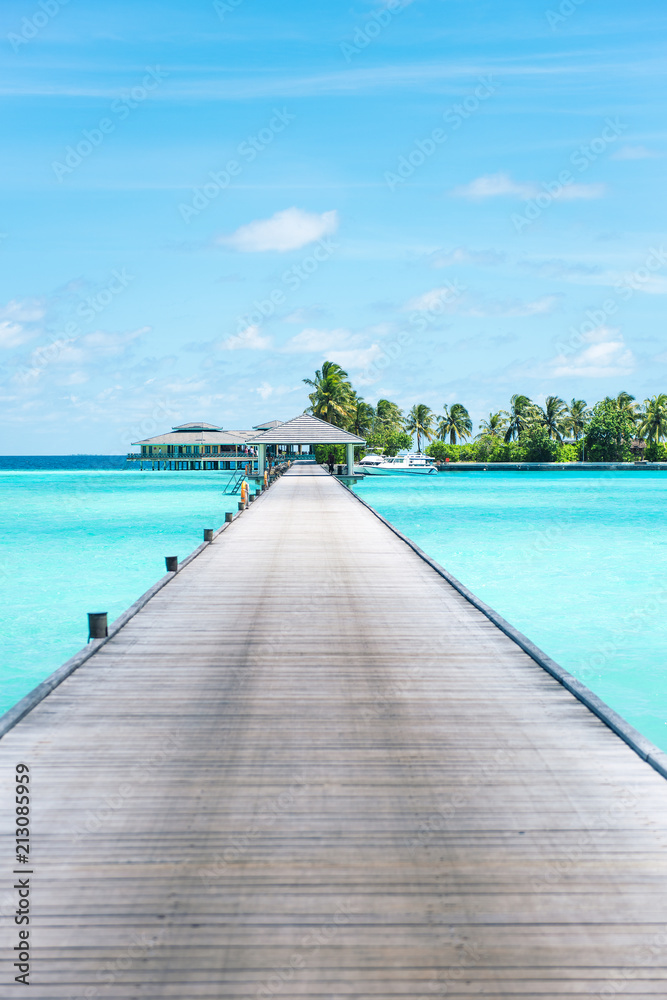 Pier at Maldives. Blue water, boats. Summer holidays photo.