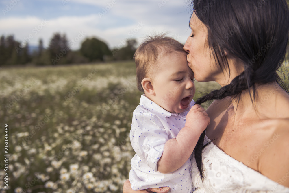 little boy and his mother enjoying outdoors in field of daisy flowers