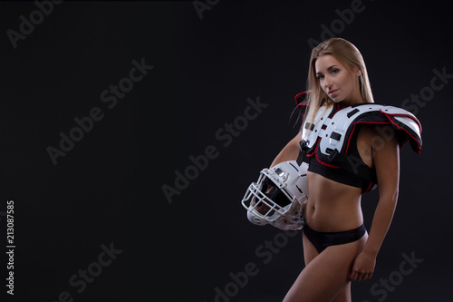 Attractive female american football player in uniform posing with helmet