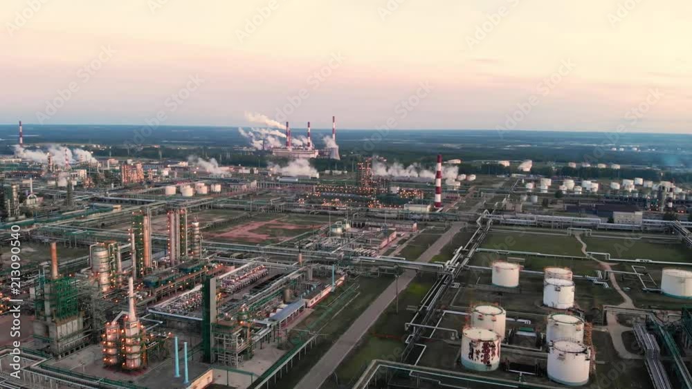 flight of the camera over the Oil refinery plant industry, Refinery factory, oil storage tank and pipeline steel with sunrise and cloudy sky background, Russia.