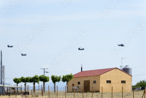 Three Boeing CH-47D Chinook helicopters flying in line with a Eurocopter Super Puma in front of the line photo