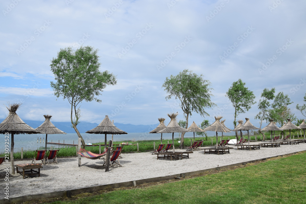 Straw umbrellas on the Lake Skadar beach. Albania - Montenegro border.