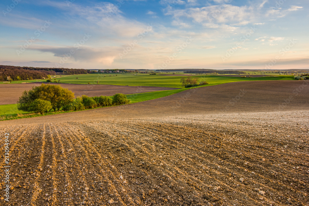 Rural landscape shot. Fields during spring. Farming, agriculture. Colorful scene during sunset. Green, brown, blue. Rural landscape shot. Fields during spring. Farming, agriculture. Colorful scene during sunset. Green, brown, blue.