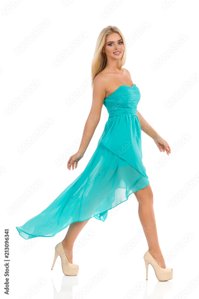Fashion Model In Turquoise Dress Is Walking And Looking At Camera