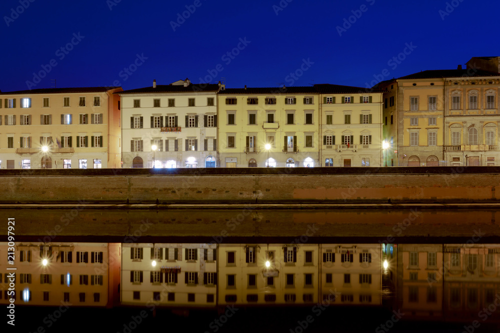 Pisa city, along river at night.
