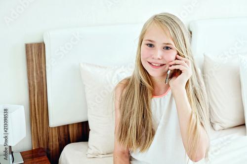 Teenage Girl Lying On Bed Using A Mobile Phone