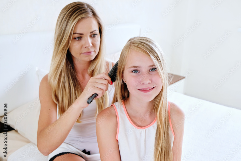 Mother brushing long hair of her daughter at home Mother brushing long hair of her daughter at home