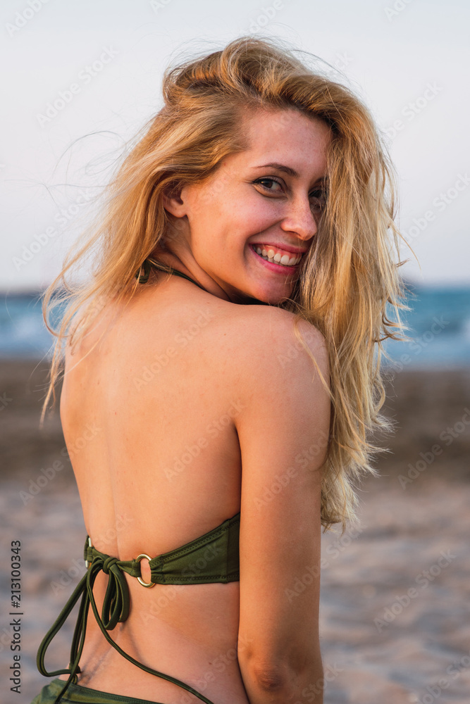 Cheerful woman in bikini sitting on sand Cheerful woman in bikini sitting on sand