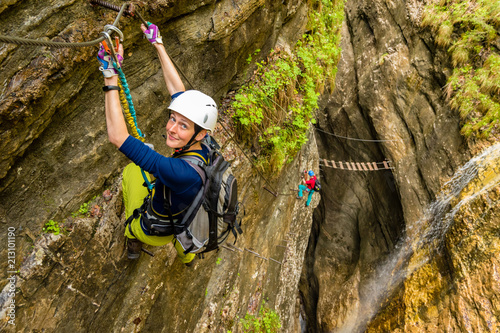 Active young girl on via ferrata in deep canyon creek with waterfall in background  Postalmklamm  Austria