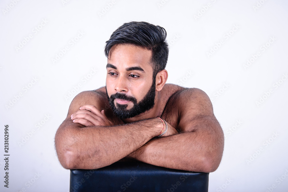Closeup portrait of young handsome thoughtful Asian man sitting on leather chair, on white background Closeup portrait of young handsome thoughtful Asian man sitting on leather chair, on white background
