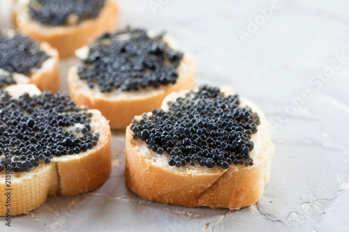 Expensive delicious black caviar white bread sandwich snack on a wooden plate
