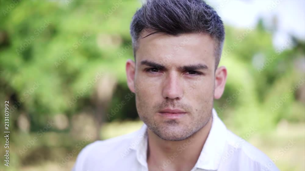 Portrait of the Attractive man who looks seriously at the camera On the green nature Background .Close up Portrait of the Attractive man who looks seriously at the camera On the green nature Background .Close up