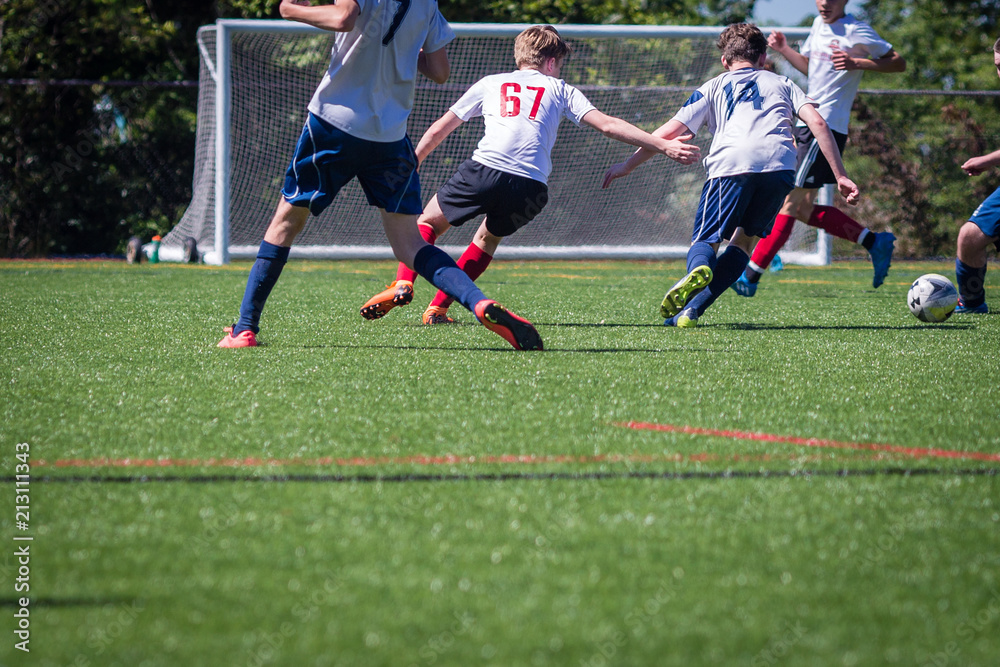 Teenage soccer players competing for the ball in front of the goal Teenage soccer players competing for the ball in front of the goal