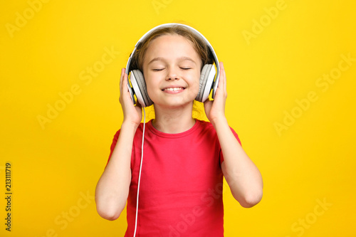 Young girl with headphones on yellow background