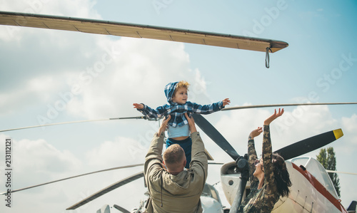 Dreaming concept. Little child dreaming about flying in sky on plane. Little son dreaming of being pilot in fathers hands at military air show. Dreaming a dream photo