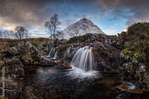 Amazing natural landscape of Scotland. A waterfall with snow covered mountain in the background. Scotland is just so beautiful.