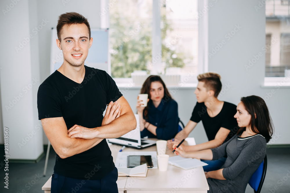 I am the part of cohesive team. Young successful man specialist portrait with colleagues meeting behind him. friendly atmosphere, communication and comradery