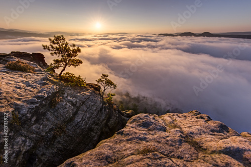 Dramatic sunrise on the rocks. Amazing sky and clouds, fog in a valley, forest. Trees, rocks, sky, peace, quiet, relax, travel, adventure.
