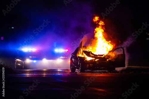 Obraz na płótnie Car on fire at night with police lights in background w salonie