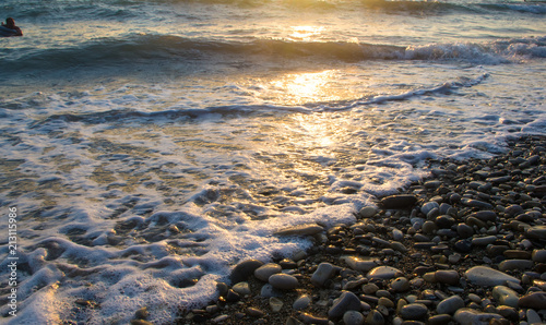 Amazing sea sunset on the pebble beach, the sun, waves, clouds